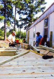 Lloyd Nutter (second from right) and volunteers construct a porch with wheelchair access outside of a home.