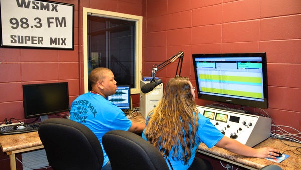 Students Brandon Craig and Summer Smitherman use a soundboard to organize music in the WSMX 98.3 Super Mix studio at LeCroy Career Tech Center