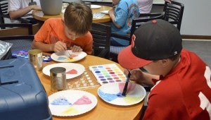 Seth Mims, 11, (pictured with baseball cap on) and Elijah Folds, 10, learn about how to mix and create colors. 