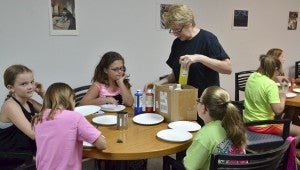 Artist Sue Anne Hoyt passes out paint to kids attending a Summer Art Camp on Thursday.