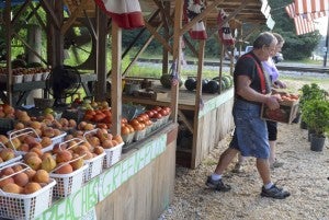 Ray’s Produce Owner Ray Pairett helps customers load peaches on Thursday morning in Maplesville.