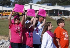 Several teachers at CMS hold up signs showing names of those who have been diagnosed with cancer.