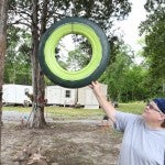 Given new life: Wanette Sims shows off a hubcap she painted in shades of green and hung from a tree. Many such decorations adorn her yard off Yellow Leaf Road. (Photos by Stephen Dawkins)